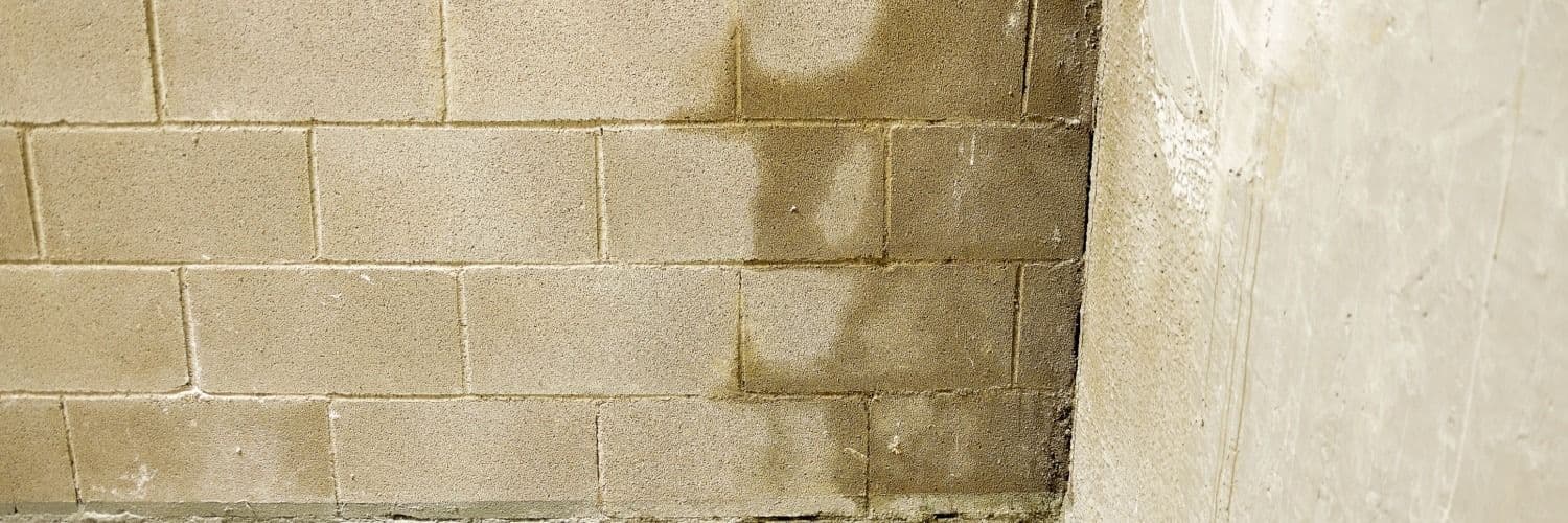 Concrete block wall with rectangular cinder blocks in running bond pattern, showing weathered tan surface and mortar joints