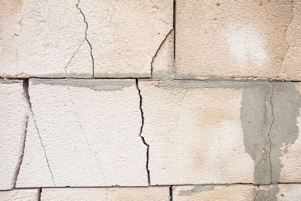 Close-up of cracked concrete or stone blocks showing structural damage and separation along mortar joints