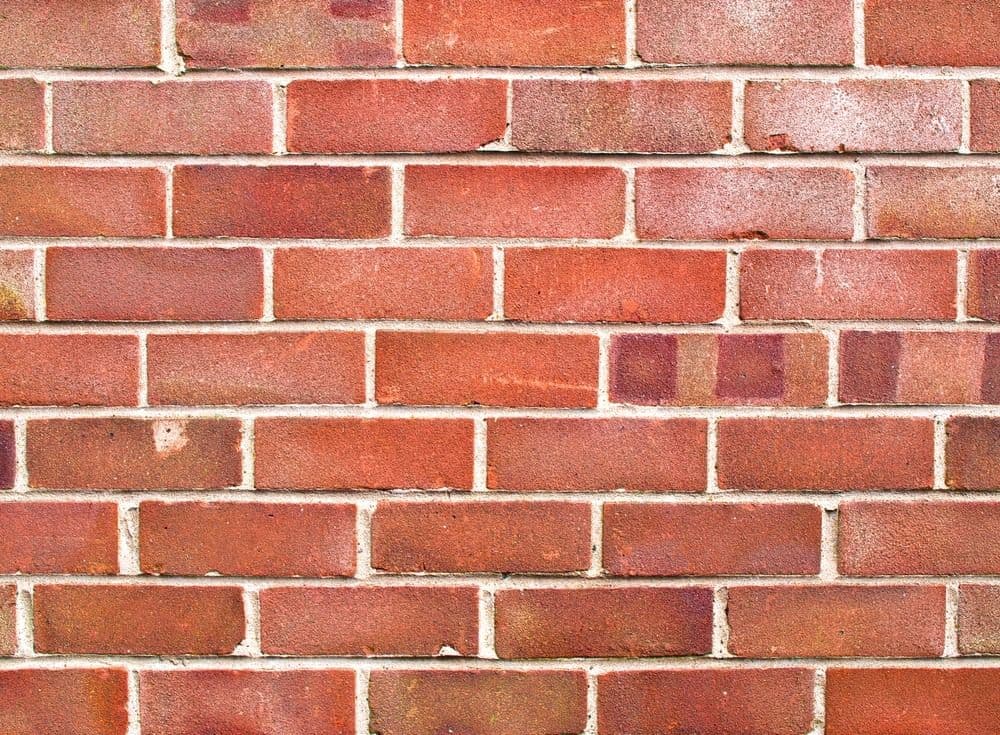 Red brick wall with white mortar joints in running bond pattern