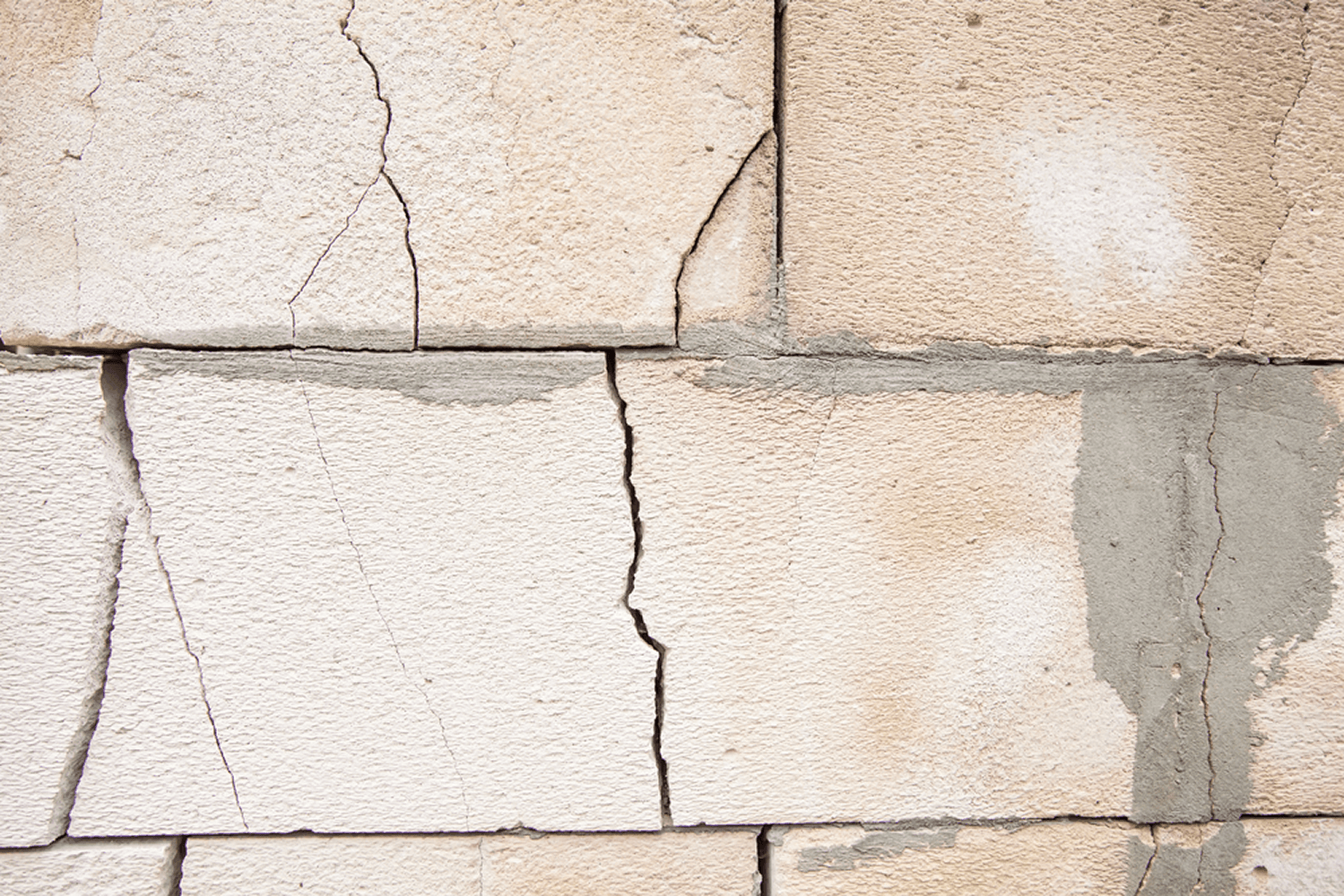 Close-up of cracked concrete blocks showing structural damage and weathering along mortar joints.