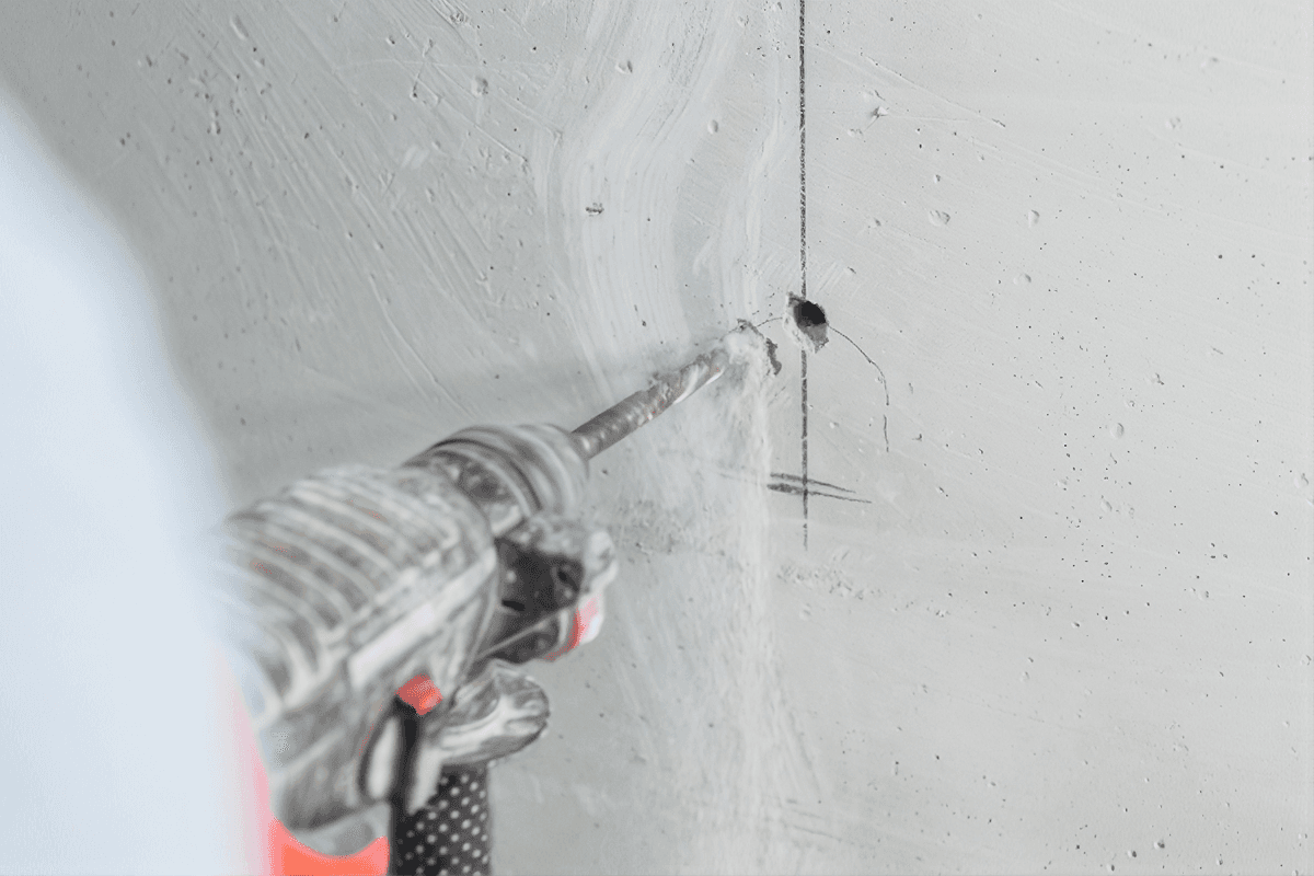 Drilling a hole in drywall with a power drill and metal bit, creating an anchor point for wall installation.